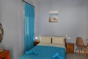 圣加利尼Manthos Holiday Home的一间卧室配有床、蓝色窗帘和椅子