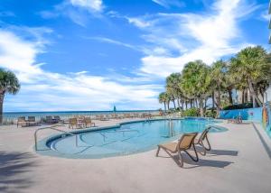 巴拿马城海滩Beachcomber Beachfront Hotel, a By The Sea Resort的海滩上带椅子和棕榈树的游泳池