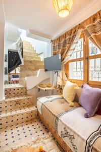 丹吉尔Dar BAB HAHA Petite Maison à la Marocaine的配有电视和楼梯的客房内的两张床