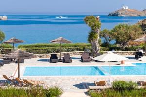 科里夏Porto Kea Suites by Sandglass的一个带椅子和遮阳伞的游泳池以及大海