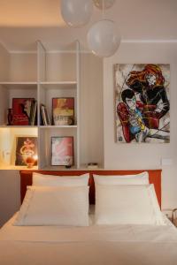 布雷西亚una stanza in carmine的一间卧室配有一张带白色床单和绘画的床。