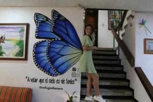 比亚维森西奥Refugio Llanero Hotel Boutique的站在蓝色蝴蝶旁边,站在墙上的小女孩