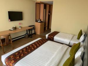 仙本那Wing Tat Grand Hotel的酒店客房设有两张床、一张桌子和一台电视。