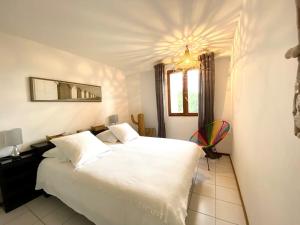 耶尔villa d'exception avec piscine , au bord de la mer的卧室配有一张白色大床和吊灯。