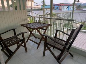 他朗168Hostel Airport@Phuket的阳台上配有一张木桌和两把椅子