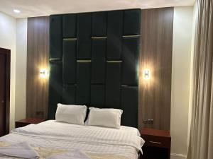 延布法克尔盐步酒店的一间卧室配有一张大床和绿色床头板