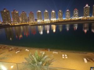 多哈Luxury Sea View Apartment with Amazing Amenities at Pearl Qatar的夜晚,一排水与城市交汇