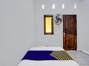 MojokertoOYO 92086 Fun Guesthouse Syariah的一间卧室配有一张黄色和蓝色毯子的床