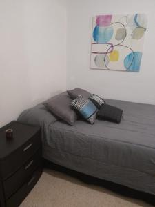 圣胡安Cozy Apartment across the San Juan Airport的一间卧室配有带枕头的床铺和床头柜