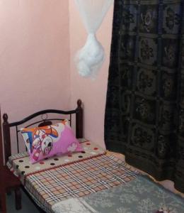 基加利Colours Club and Spa的小卧室配有带枕头和窗帘的床