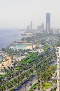 吉达Seafront Luxury Suites Jeddah Corniche的棕榈树城市和海洋的空中景观