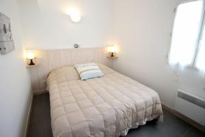 拉弗洛特Le Clos des Flots - La Dune的一间小卧室,配有一张带两盏灯的白色床