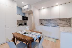 圣雷莫Ariston & Casinò - Appartamento con Giardino e Garage的厨房配有木桌和白色橱柜。
