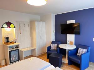 圣彼得奥尔丁Hotel Garni Dünennest的一间设有蓝色椅子、一张桌子和一台电视的房间