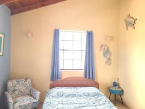 布里奇敦DonaMae 2 story Barbados House的一间卧室设有一张床、一个窗口和一把椅子