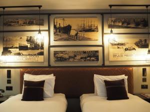 卡迪夫加的夫靛蓝酒店的两张位于酒店客房的床,墙上挂有照片