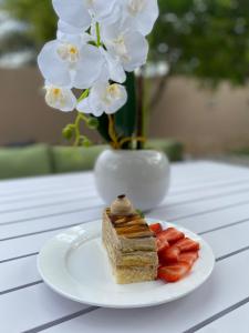 尼兹瓦Aryaf hostel的花瓶,桌子上一盘蛋糕和草莓
