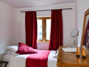 雷纳姆Oakwell Lodge的一间卧室配有一张带红色窗帘的床和一扇窗户