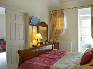 阿克斯明斯特Porters Lodge的卧室配有一张床,墙上配有电视。