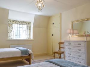 BensonDulcie Cottage的一间卧室配有两张床、一个梳妆台和镜子