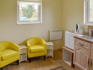 YaldingShepherds Hut 1 At Laddingford - Uk32531的厨房配有2把黄色椅子和桌子