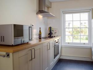 莱德伯里The Cottage的厨房配有白色橱柜、微波炉和窗户。