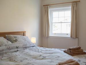 莱德伯里The Cottage的卧室内的一张未铺好的床,设有窗户