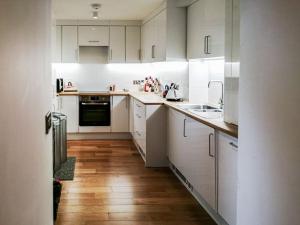 奥本Kilbowie Retreat的白色的厨房铺有木地板,配有白色橱柜。