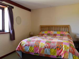 Saint EndellionStable Cottage - Uk12088的一间卧室配有一张带五颜六色被子的床