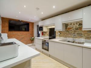 Bowness-on-SolwayThe Barnacle Goose - Uk35261的厨房配有白色橱柜和石墙