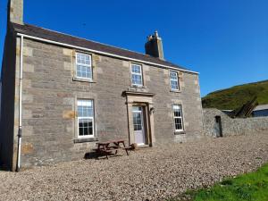 MachrihanishBallygroggan Farmhouse - Uk35208的石头建筑,前面设有野餐桌