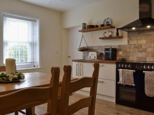 BlencogoBlaithwaite Cottage的厨房配有木桌、桌子和炉灶。