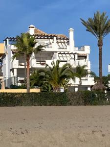 卡拉德米哈斯ARRUZAFA PLAYA Beachfront apartment La Cala de Mijas的一座白色的建筑,前面有棕榈树