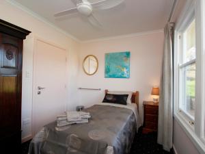 汉道夫Hill Cottage Hahndorf的一间卧室配有一张带吊扇和窗户的床。