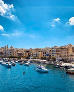 森格莱阿New & unique apartment - A 5 minutes ferry to capital city of Valletta的一群船停靠在港口,有建筑物