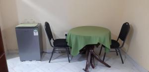 迪亚尼海滩Armaan Guest House的一张绿色桌子和四把椅子,旁边是冰箱