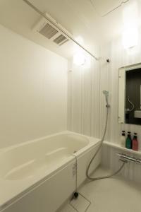 名古屋Japan Hinata Hotel 池下駅徒歩2分 1LDK 50平米 8名的带浴缸的白色浴室和电视。