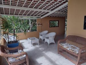巴纳内拉斯CASA DA MONTANHA na Chácara Paraíso的门廊配有藤椅、沙发和桌子