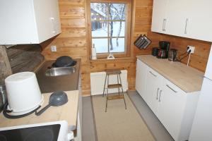 萨利色尔卡Kuukkeli Log Houses Aurora Cabin - Jaspis的一间小厨房,配有白色的橱柜和凳子