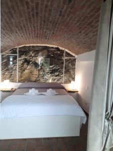 马纳罗拉Olimpo Affittacamere的卧室配有白色的床铺和石墙