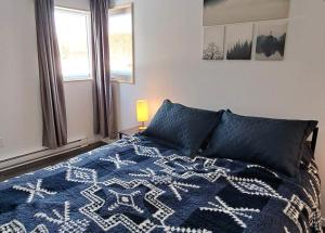 圣亚历克西德蒙Les Chalets Double K # 2的一间卧室配有一张带蓝色毯子的床和窗户。