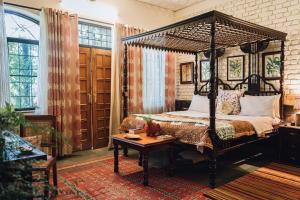 德拉敦Gorayya Villa的一间卧室配有一张天蓬床和一张桌子
