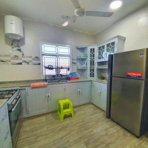 Sayqalreaambreather2的厨房配有不锈钢冰箱和黄色凳子