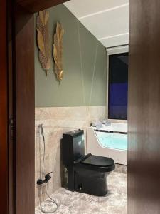 利雅德The Palms Resort (3)的浴室配有黑色卫生间和浴缸。