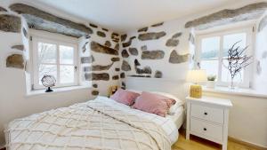 舒马瓦山区霍日采Romantická chalupa s krbem的一间卧室设有一张床和石墙