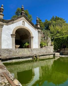 Vale de PrazeresQuinta da Porta - Solar de Vale de Prazeres的花园池塘上的石拱门