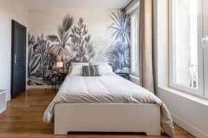 旺多姆L'Orée du Faubourg - VENDOME CENTRE的一间卧室配有一张白色床和热带壁纸