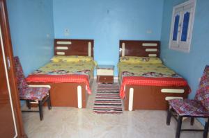 阿斯旺Golden nubian guesthouse的一间设有两张床和两把椅子的房间