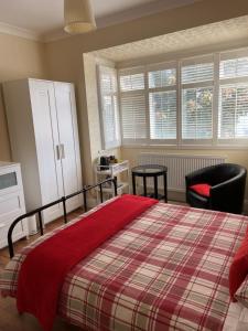 伦敦Streatham Common Bed & Breakfast的一间卧室配有一张床、一把椅子和窗户。