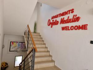 梅杜林Apartments Medulin - Orijeta的带有国语标志的楼梯,欢迎来自梅勒斯的国民
